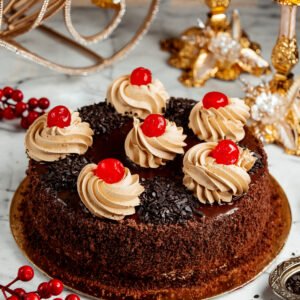 sideview of chocolate cake with whipped cream and cherries on the table